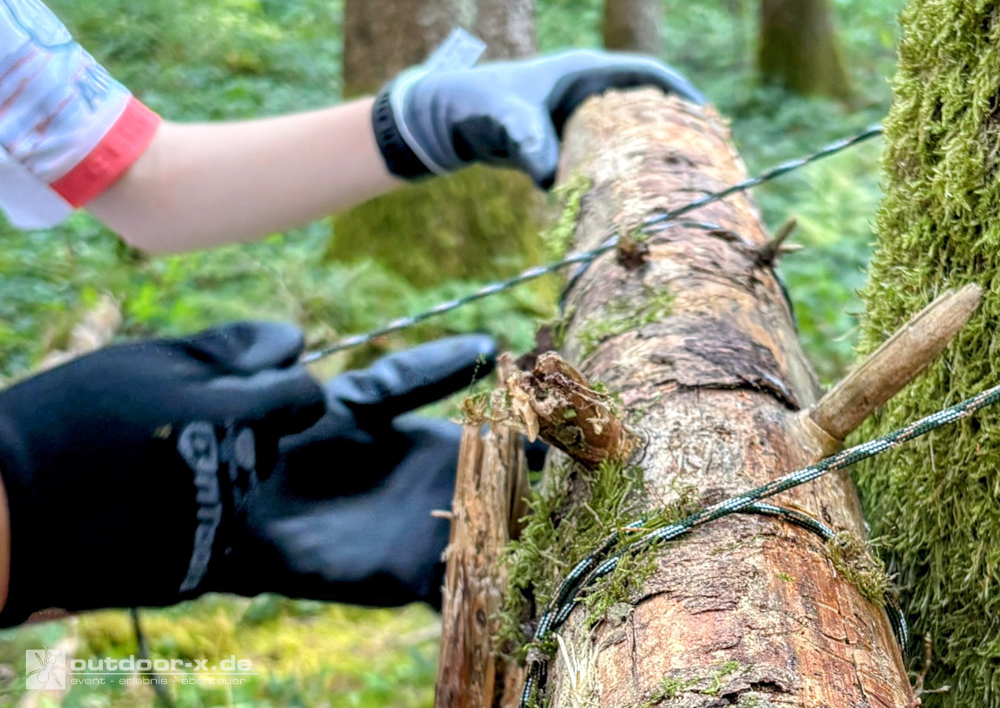 Schülerinnen und Schüler errichten beim Teambuilding für Schulklassen einen Shelter aus Naturmaterialien im Wald